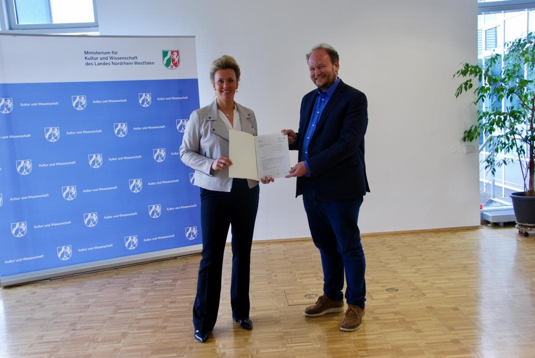 Ina Brandes, Wissenschaftsministerin von Nordrhein-Westfalen, und Klaus von Stosch mit dem Vertrag für das Verbundprojekt zwischen den Universitäten Bonn und Paderborn, an dem auch das House of One aktiv mitwirkt.